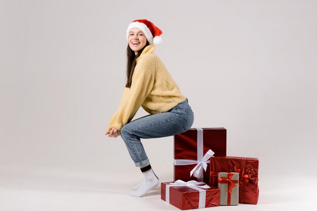 Photo jeune femme joyeuse assise sur une pile de boîtes de noël isolées sur un fond blanc