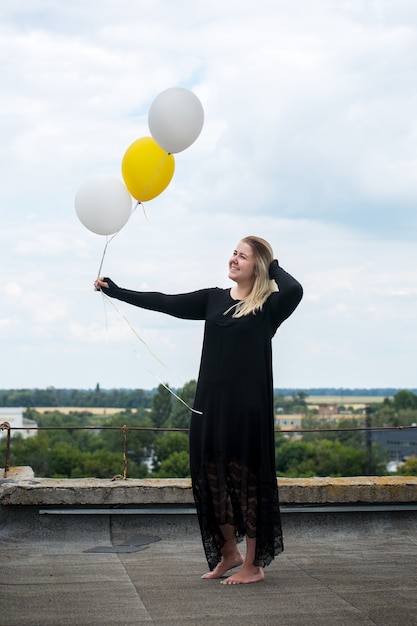 Jeune femme joyeuse avec des ballons sur le toit