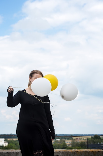 Jeune femme joyeuse avec des ballons sur le toit