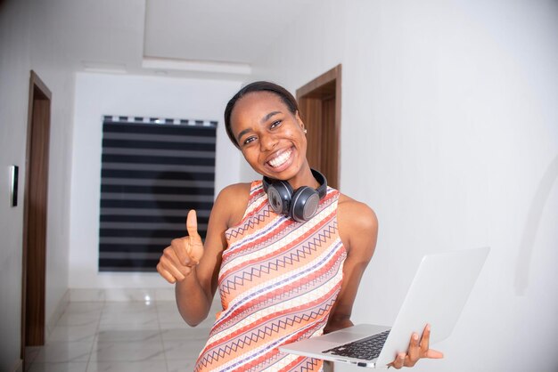 Une jeune femme joyeuse célèbre sa réalisation en lisant de bonnes nouvelles sur son ordinateur portable.