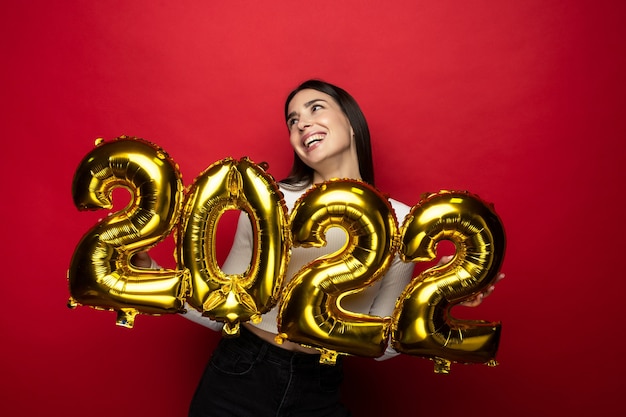 Une jeune femme joyeuse détient les chiffres 2022. Noël à venir