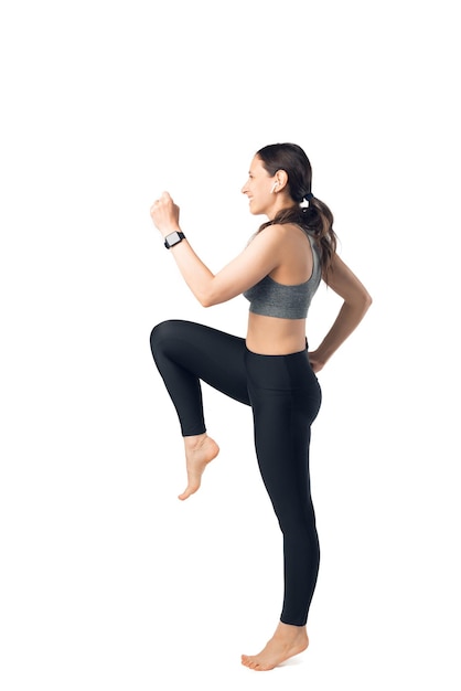 Une jeune femme joyeuse fait du sport dans un studio blanc.