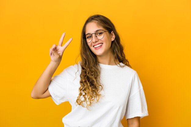 Jeune femme joyeuse et insouciante montrant un symbole de paix avec les doigts