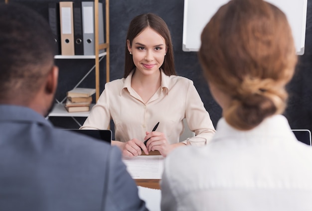 Jeune femme joyeuse interviewant par deux hommes d'affaires au bureau