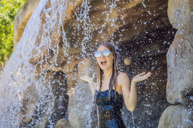 Jeune femme joyeuse sous les sources chaudes du spa de jour de la piscine du ruisseau d'eau