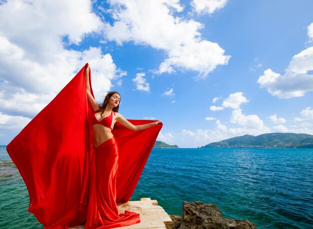 Jeune femme avec jupe rouge et tissu comme des ailes. Style vogue.