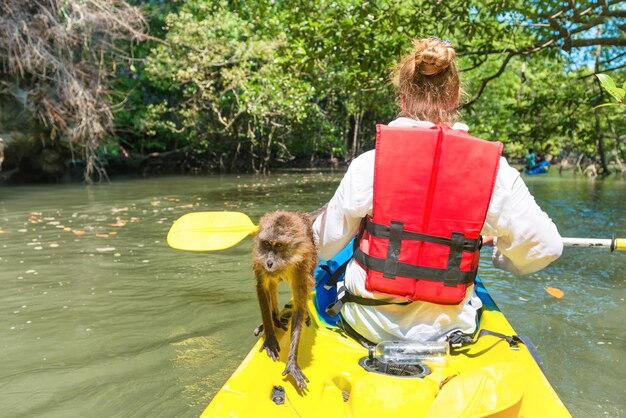 Jeune femme kayak sur canoë avec singe sauvage