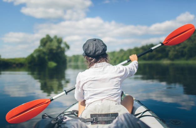 Jeune femme kayak seul sur une rivière sans gilet de sécurité. Voyager seul. Période de vacances à l'extérieur. Belle nature et journée ensoleillée.