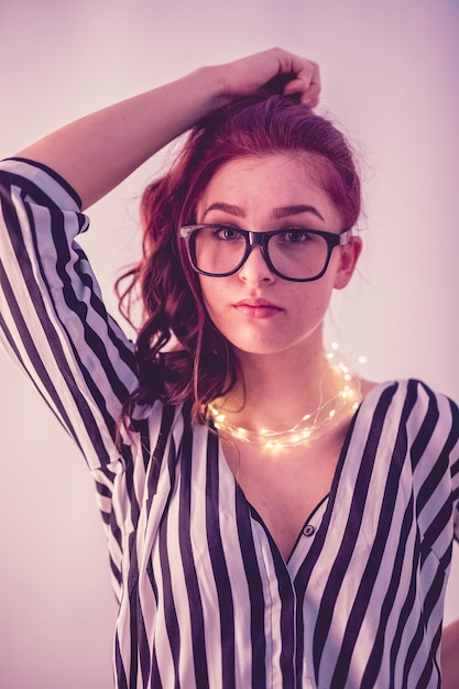 Photo jeune femme avec une lampe à cordes éclairée sur un fond gris