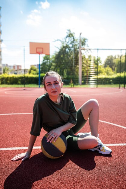 Une jeune femme lance un ballon de basket à l'extérieur par une journée ensoleillée