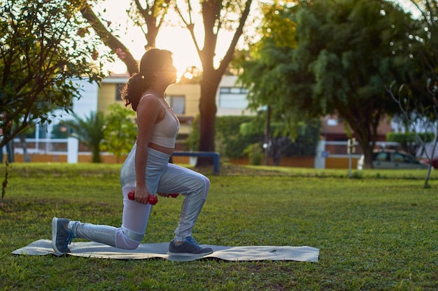 Jeune femme latina exerce avec des haltères dans parkxA