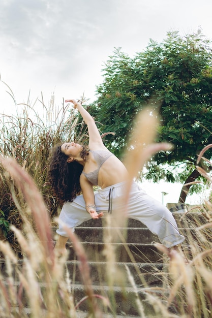 Jeune femme latina qui s'étend sur le côté de son dos au milieu d'exercices de respiration dans la nature