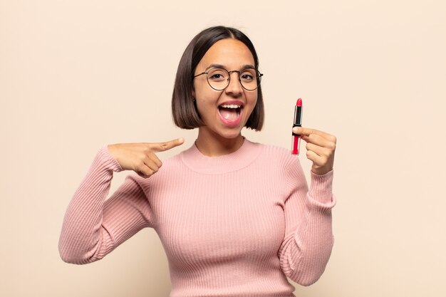 Jeune femme latine à l'air excitée et surprise pointant vers le côté et vers le haut pour copier l'espace