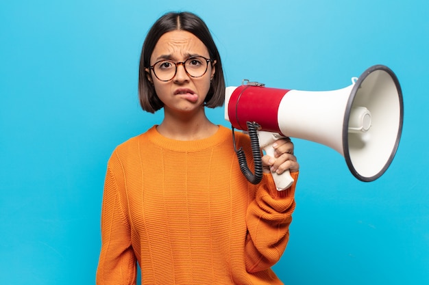 Jeune femme latine à l'air perplexe et confuse, mordant la lèvre avec un geste nerveux, ne connaissant pas la réponse au problème