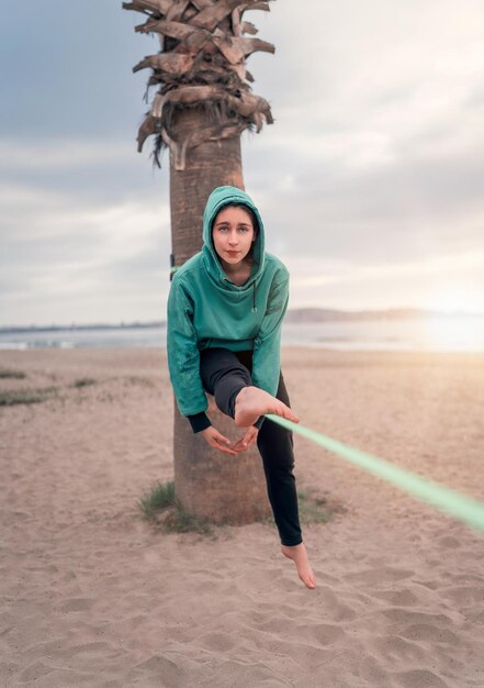 Jeune femme latine assise et en équilibre sur le mou de la sangle de yoga à la plage de La Serena