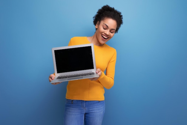 Jeune femme latine aux cheveux afro travaillant à distance à l'aide d'un ordinateur portable sur fond de studio