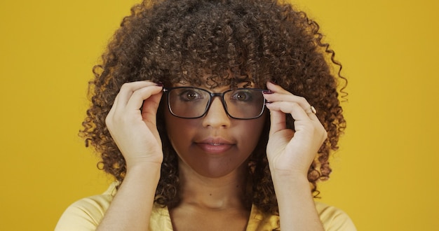 Jeune femme latine aux cheveux bouclés heureuse avec ses lunettes. Concept de soins oculaires.