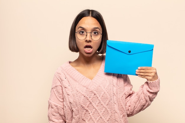 Jeune femme latine ayant l'air très choquée ou surprise, regardant la bouche ouverte en disant wow