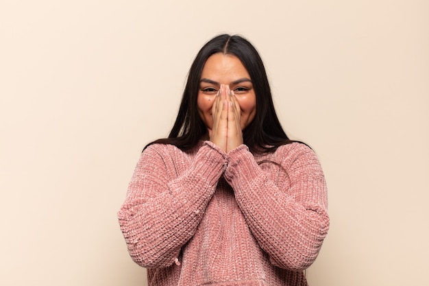 Jeune femme latine à la bouche heureuse, joyeuse, chanceuse et surprise couvrant les deux mains