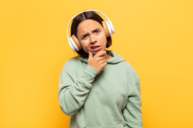 Jeune femme latine avec la bouche et les yeux grands ouverts et la main sur le menton, se sentant désagréablement choquée, disant quoi ou wow