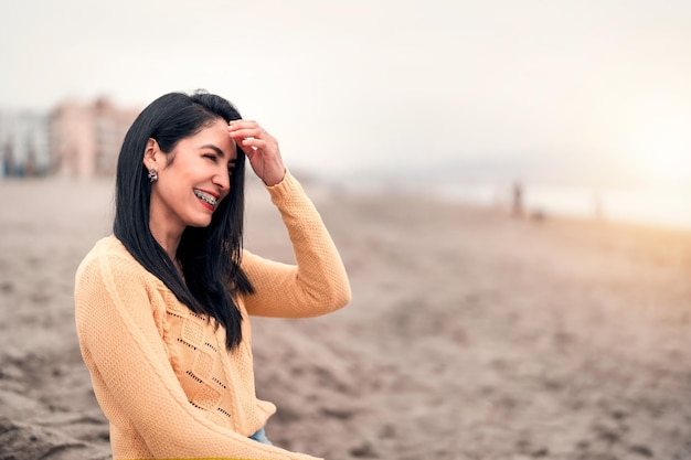 Jeune femme latine à bretelles riant sur le portrait de la plage