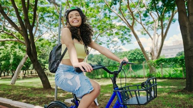 Jeune femme latine en casque de protection fait du vélo le long de la piste cyclable dans un parc de la ville
