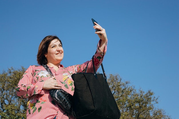 Jeune femme latine caucasienne prend un selfie pour envoyer un message photo à son partenaire