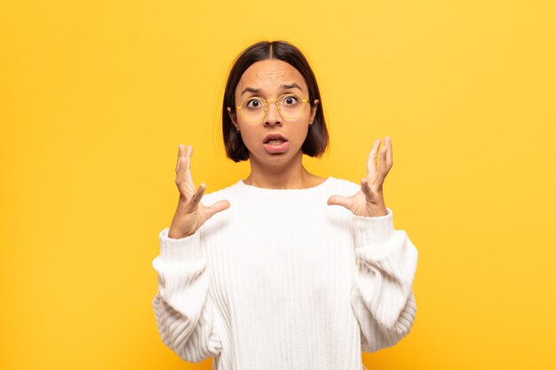 Jeune femme latine crier avec les mains en l'air, se sentir furieux, frustré, stressé et bouleversé