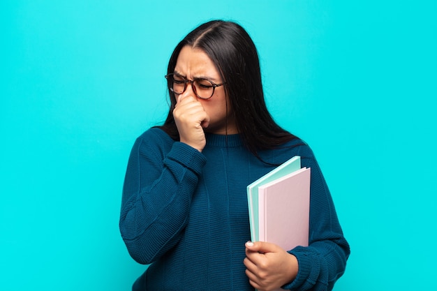 Jeune femme latine dégoûtée, tenant le nez pour éviter de sentir une odeur nauséabonde et désagréable