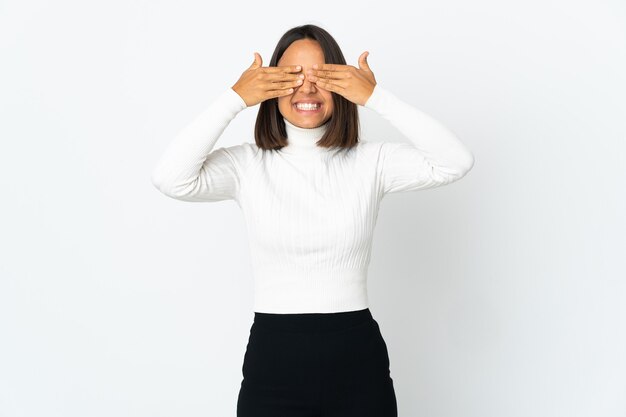 Jeune femme latine isolée couvrant les yeux par les mains et souriant