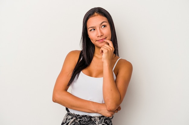 Jeune femme latine isolée sur fond blanc détendue en pensant à quelque chose en regardant un espace de copie.