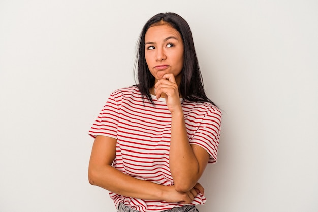 Jeune femme latine isolée sur fond blanc détendue en pensant à quelque chose en regardant un espace de copie.