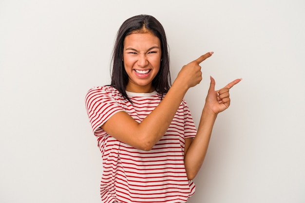 Jeune femme latine isolée sur fond blanc excité pointant avec les index loin.