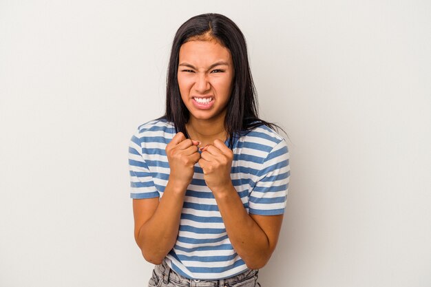 Jeune femme latine isolée sur fond blanc montrant le poing à la caméra, expression faciale agressive.