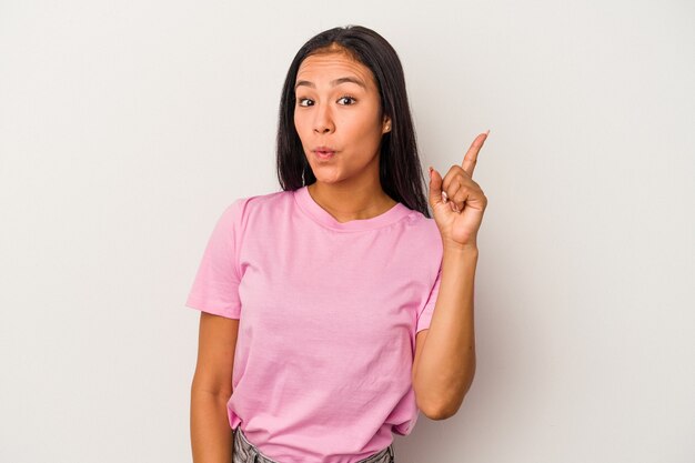 Jeune femme latine isolée sur fond blanc pointant vers le haut avec la bouche ouverte.