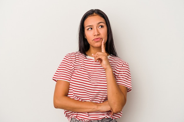 Jeune femme latine isolée sur fond blanc regardant de côté avec une expression douteuse et sceptique.