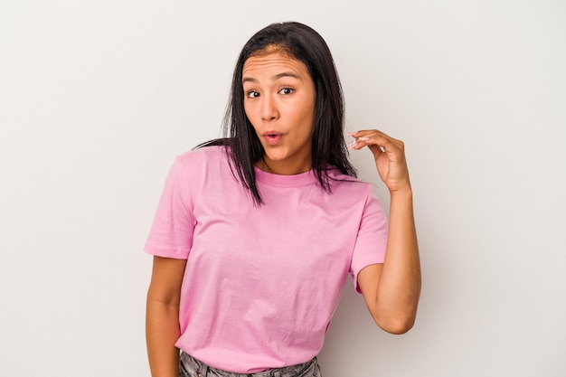 Jeune femme latine isolée sur fond blanc en riant de quelque chose, couvrant la bouche avec les mains.