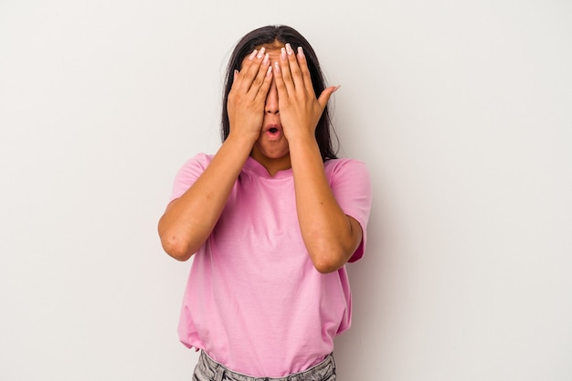 Jeune femme latine isolée sur fond blanc s'amusant couvrant la moitié du visage avec la paume.