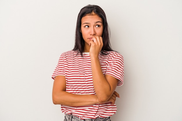 Jeune femme latine isolée sur fond blanc se rongeant les ongles, nerveuse et très anxieuse.