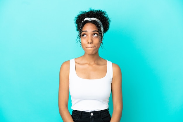 Jeune femme latine isolée sur fond bleu ayant des doutes en levant les yeux