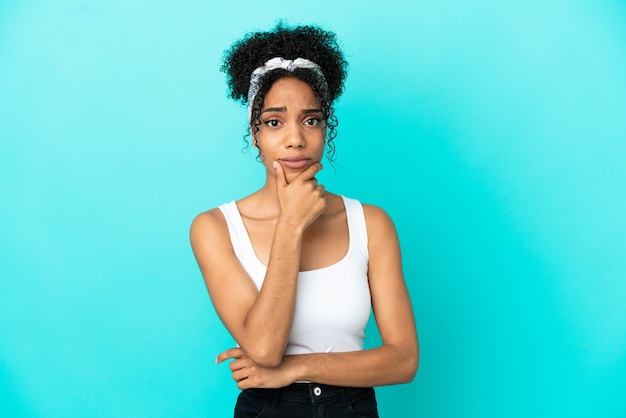 Jeune femme latine isolée sur fond bleu ayant des doutes