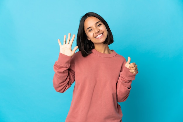 Jeune femme latine isolée sur fond bleu comptant six avec les doigts