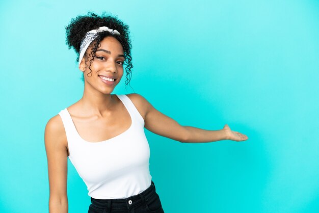 Jeune femme latine isolée sur fond bleu étendant les mains sur le côté pour inviter à venir