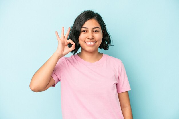 Jeune femme latine isolée sur fond bleu gaie et confiante montrant un geste correct.