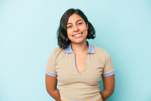 Jeune femme latine isolée sur fond bleu heureuse, souriante et gaie.