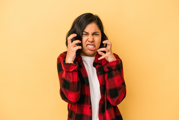 Jeune femme latine isolée sur fond jaune contrariée en criant avec les mains tendues.