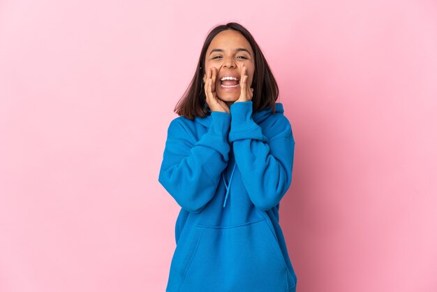 Jeune femme latine isolée sur fond rose criant et annonçant quelque chose