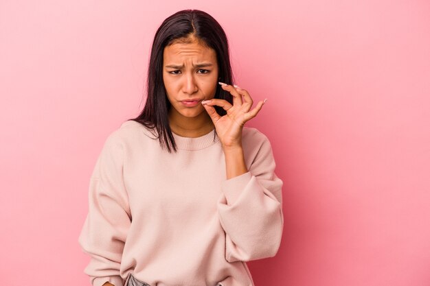 Jeune femme latine isolée sur fond rose avec les doigts sur les lèvres gardant un secret.