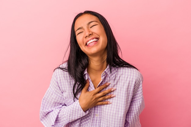 Jeune femme latine isolée sur fond rose éclate de rire en gardant la main sur la poitrine.