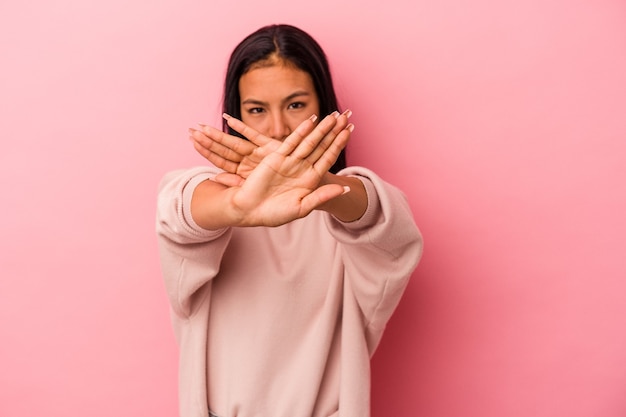 Jeune femme latine isolée sur fond rose faisant un geste de déni